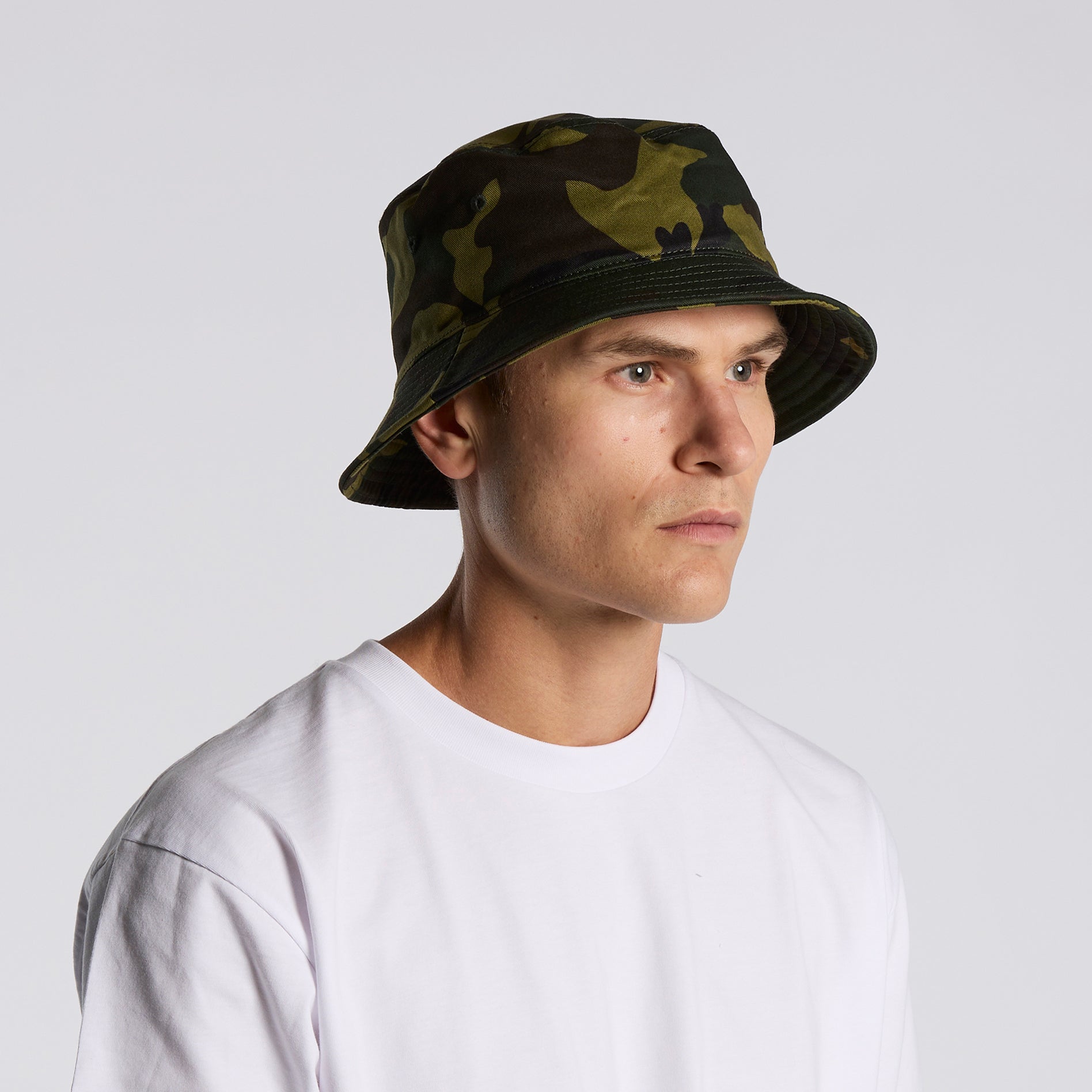 Person wearing as colour camouflage bucket hat  viewed from the side against a plain background
