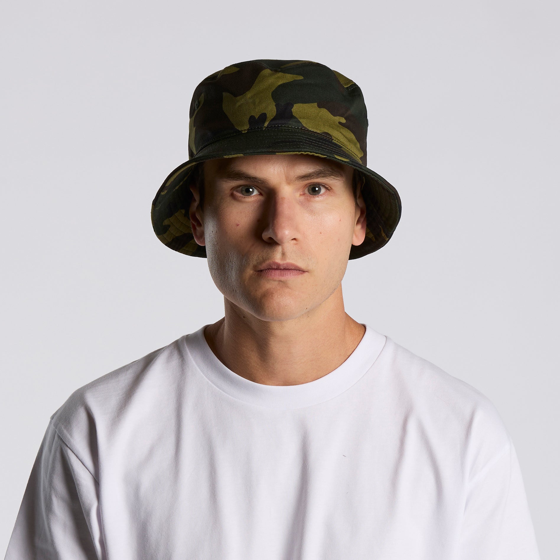 Person wearing as colour camouflage bucket hat and white t-shirt on a plain background