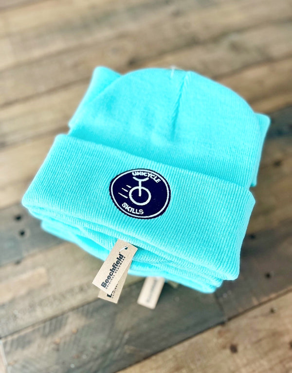 Turquoise beanie with a logo on a wooden surface