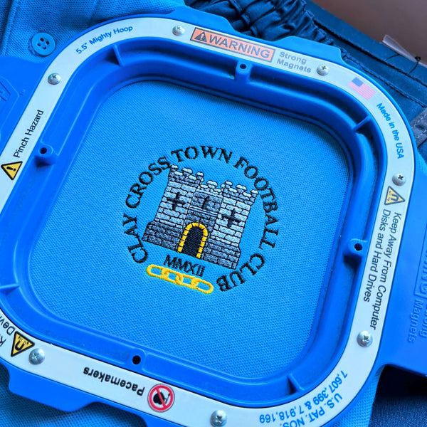 Embroidered polo shirt with 'Clay Cross Town Football Club' logo still in embroidery frame