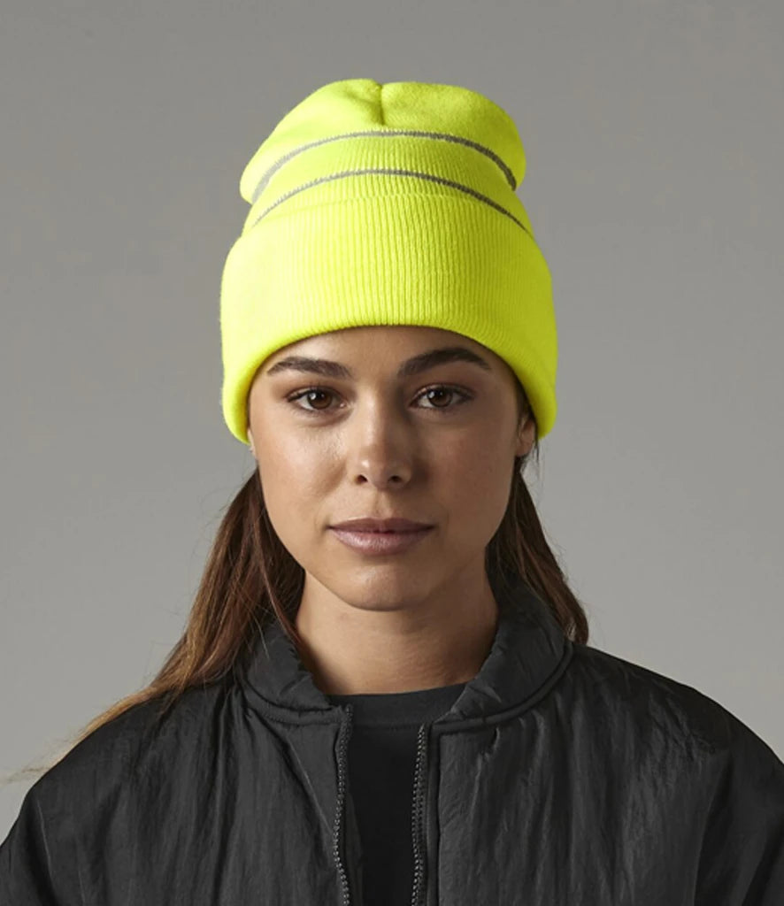 female model wearing Beechfield Enhanced-Viz Beanie in colour fluorescent yellow photographed from the front on a grey background
