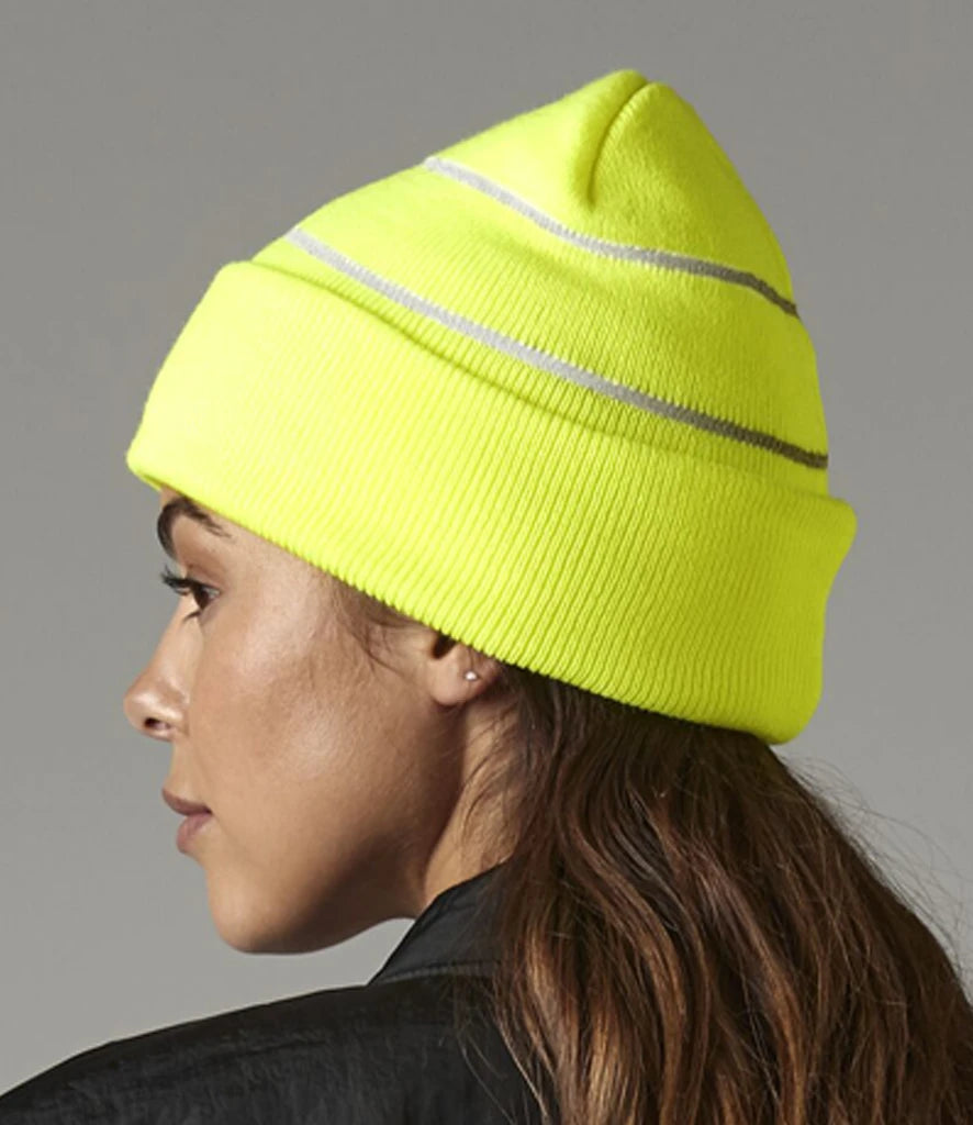 female model wearing Beechfield Enhanced-Viz Beanie in colour fluorescent yellow photographed from the side on a grey background
