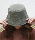 Person wearing a vintage green denim bucket hat with a plain background