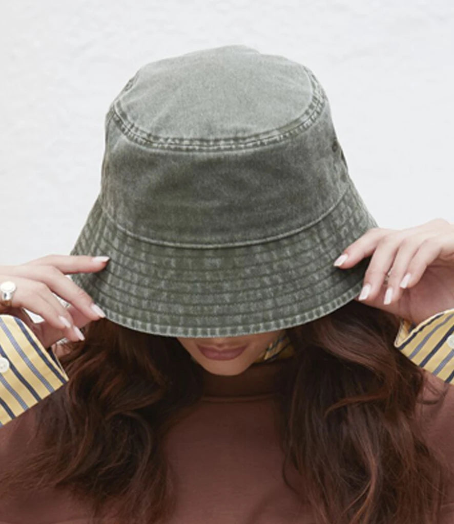 Person wearing a vintage green denim bucket hat with a plain background