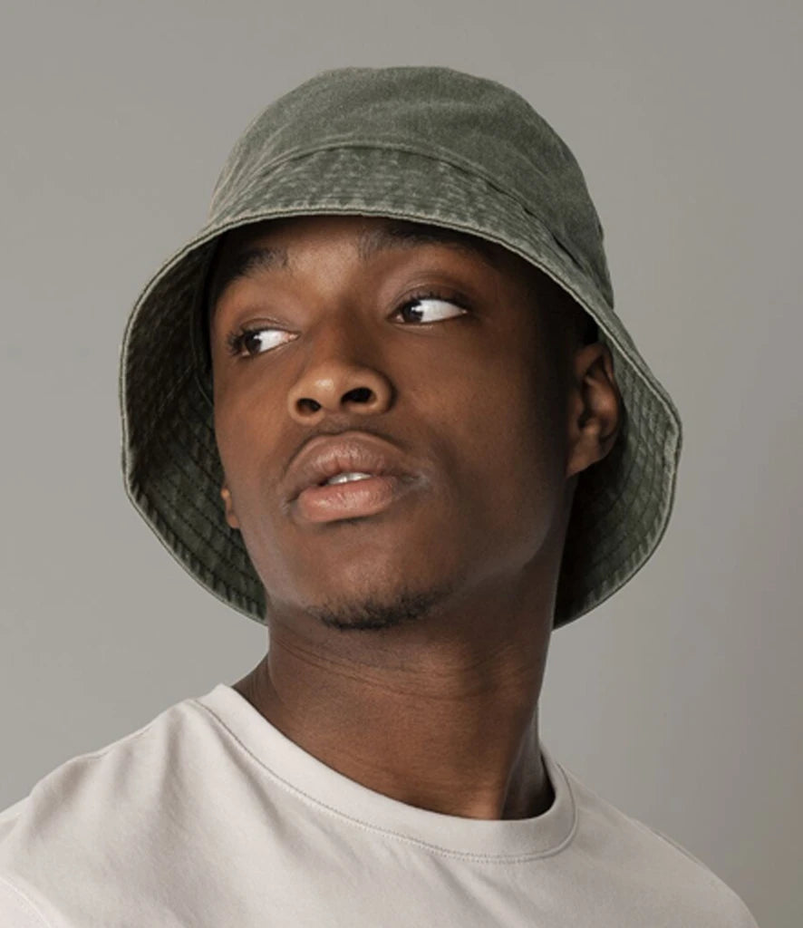 Person wearing a vintage green bucket hat against a grey background