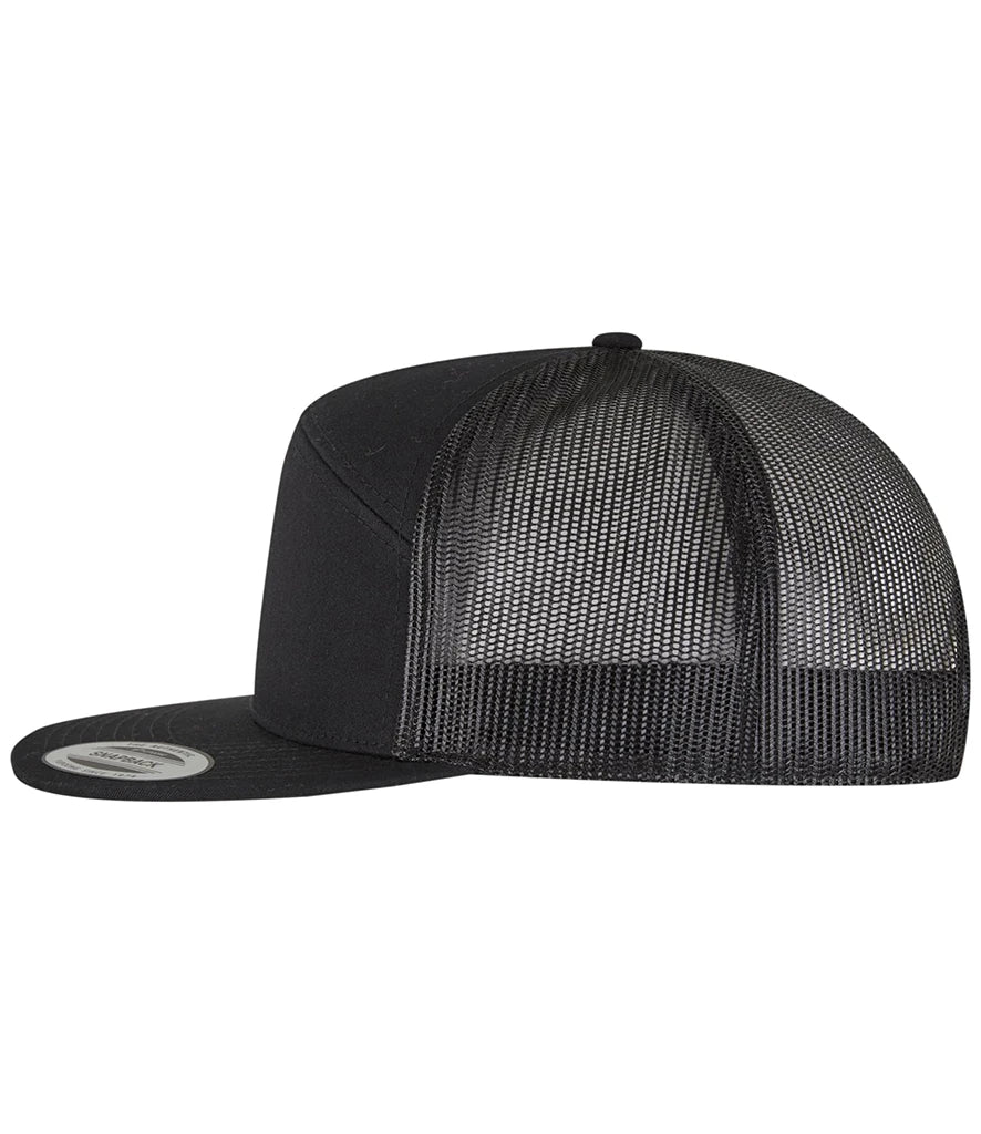 black Flexfit 7 Panel Trucker Cap viewed from the side on a white background