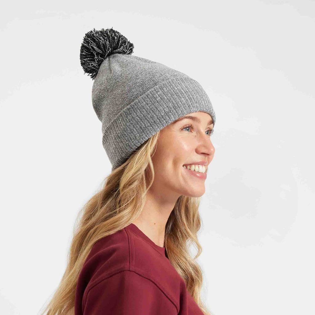 Woman wearing a gray knit beanie with a pom-pom on a white background
