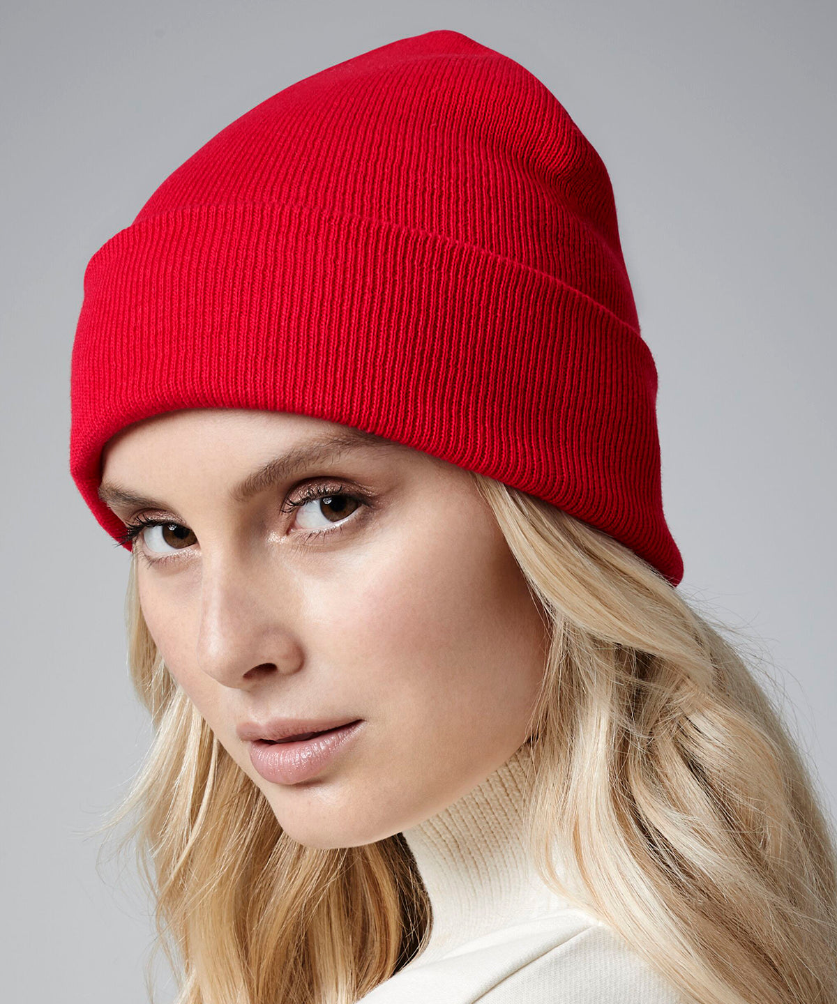 female model wearing Beechfield Organic Cotton Original Cuffed Beanie in colour classic red shot on a white background
