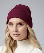 female model wearing Beechfield Organic Cotton Original Cuffed Beanie in colour burgundy shot on a white background
