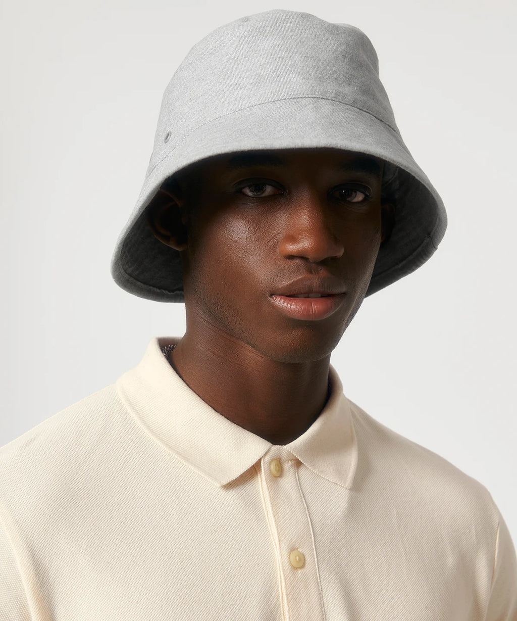 Man wearing heather grey stanley stella bucket hat with metal eyelets on a white background