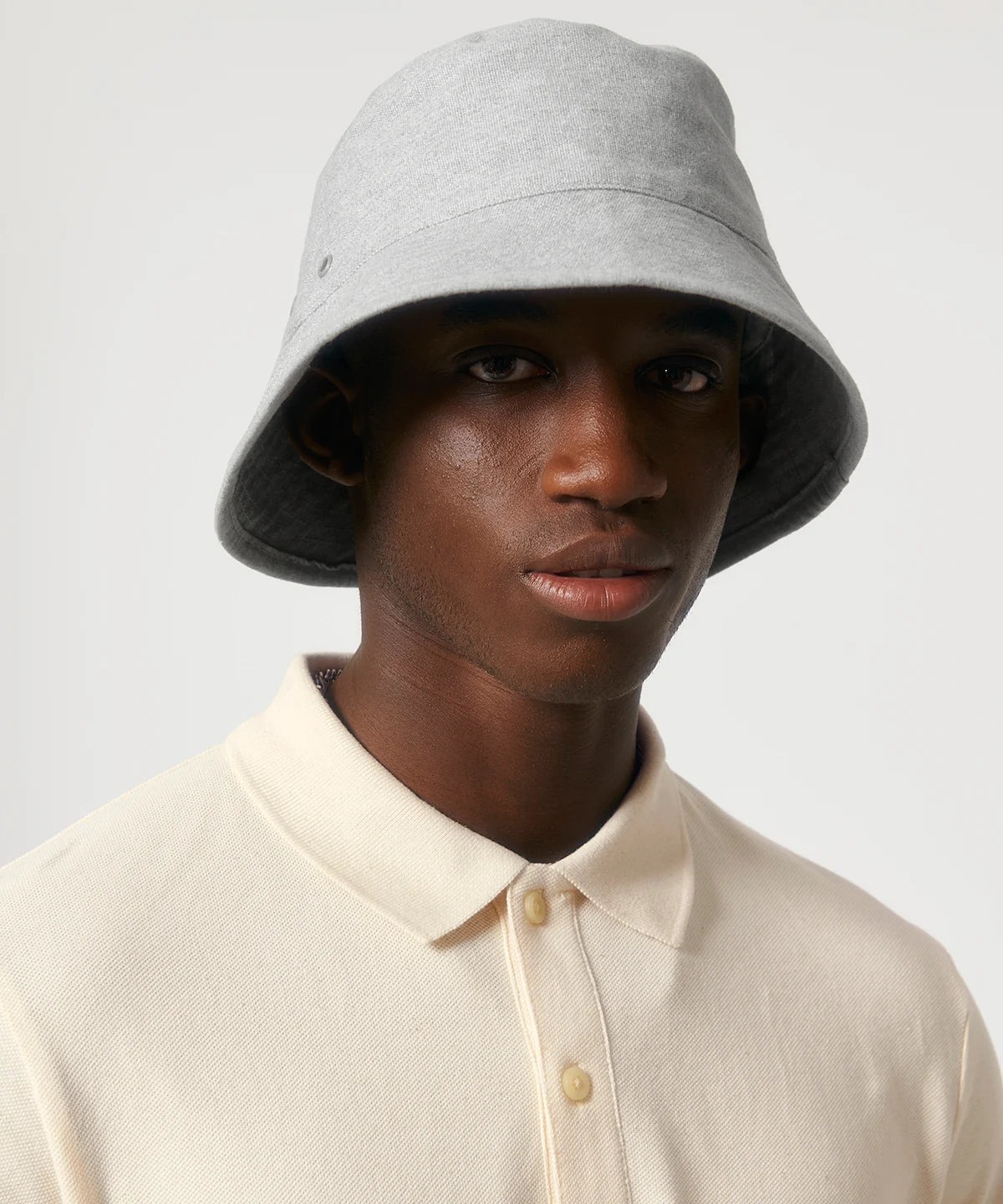 Man wearing heather grey stanley stella bucket hat with metal eyelets on a white background