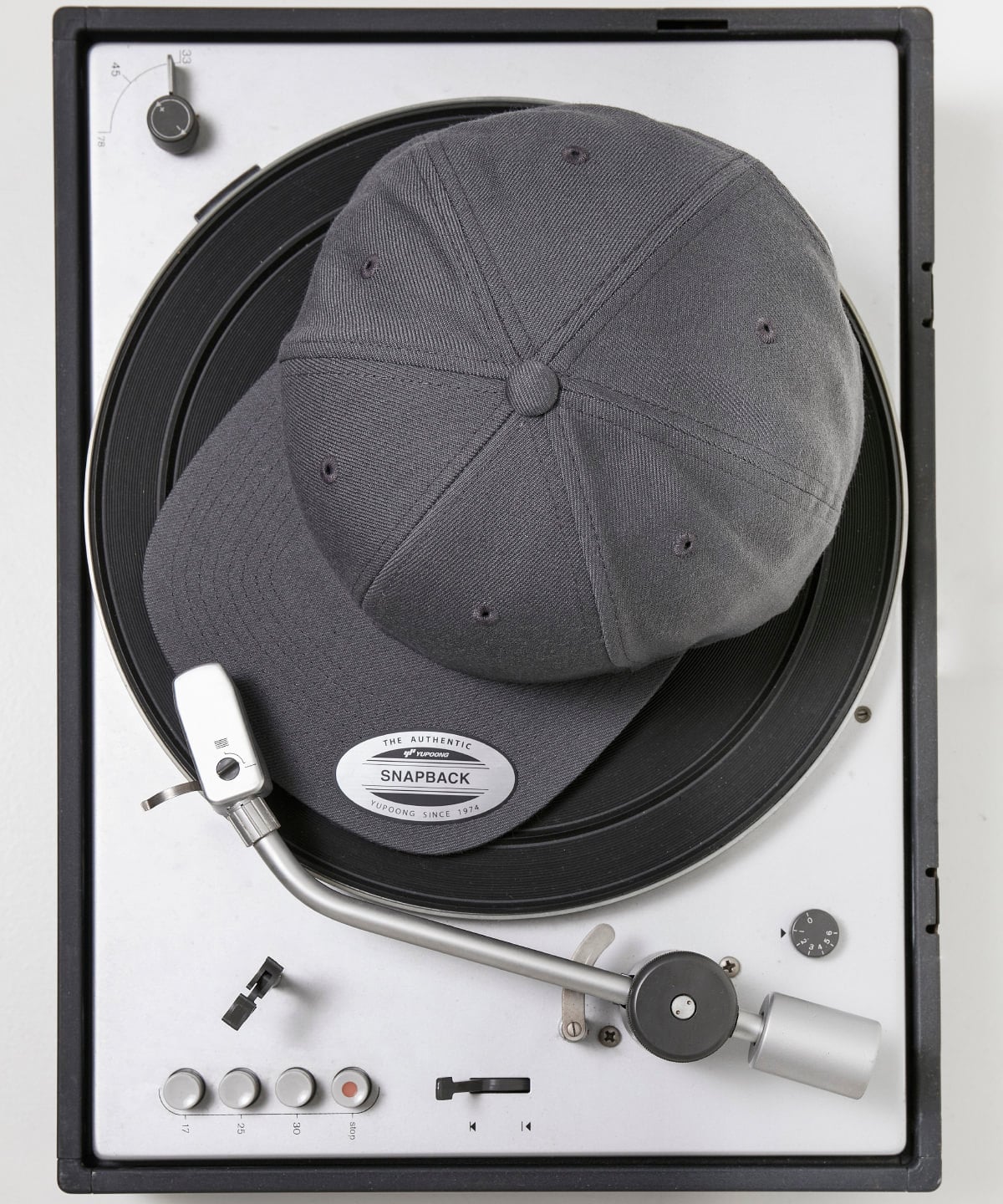 product image of flexfit classic snapback baseball cap in the colour dark grey viewed from above photographed on a record turntable