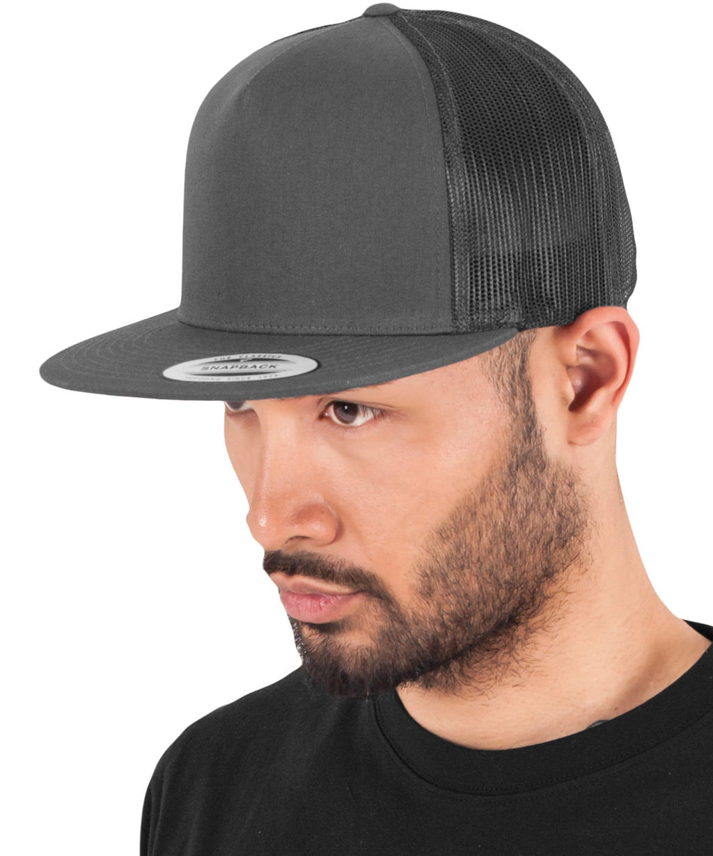 model image of male wearing flexfit classic trucker cap in the colour charcoal viewed from the side photographed on a white background